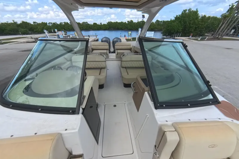 Slide: The Image of 2018 Regal 29 OBX boat interior with seating and windshield, docked by a scenic waterway. - 49