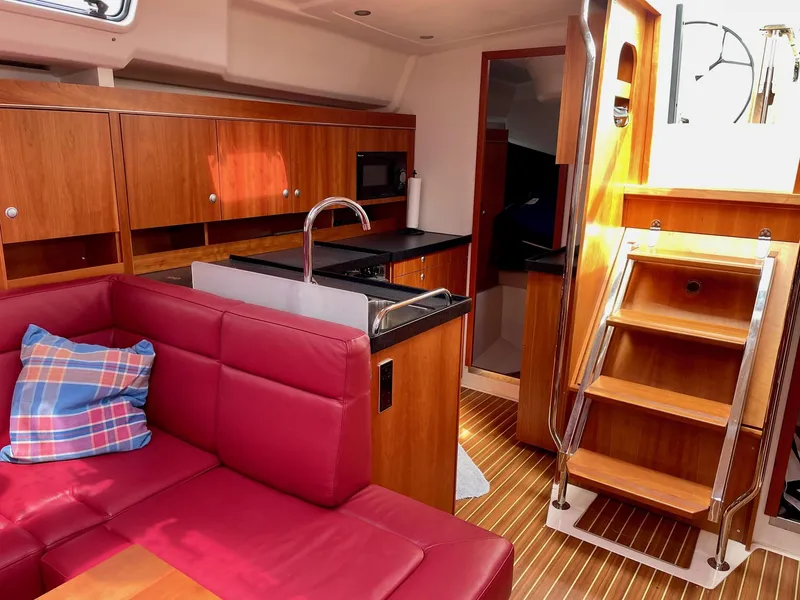 Slide: The Image of Interior of a 2016 Hanse 455 yacht with red sofa and wooden kitchen. - 12