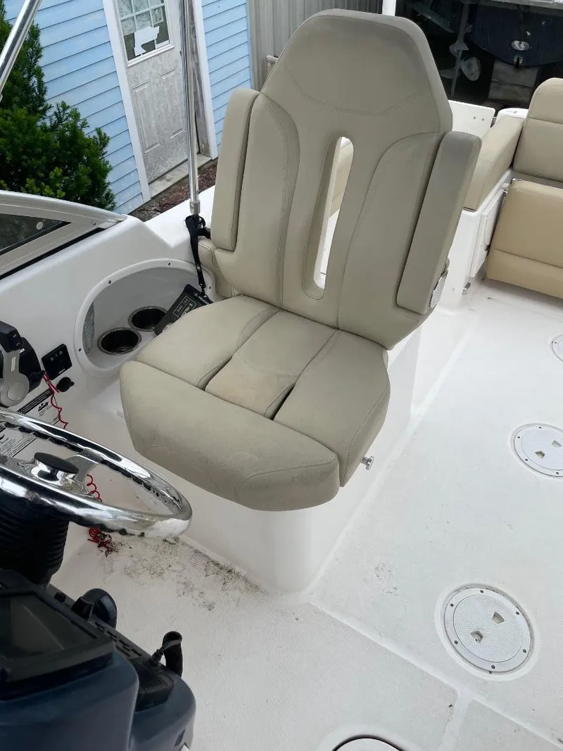 Slide: The Image of 2016 Pursuit DC 235 Dual Console boat interior with beige captain's chair and steering wheel. - 11