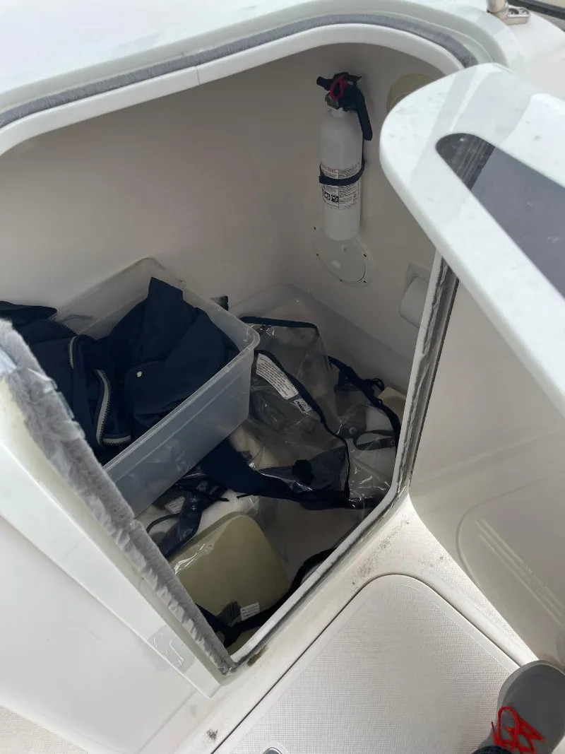 Slide: The Image of Storage compartment of a 2016 Pursuit DC 235 Dual Console boat with safety equipment. - 16