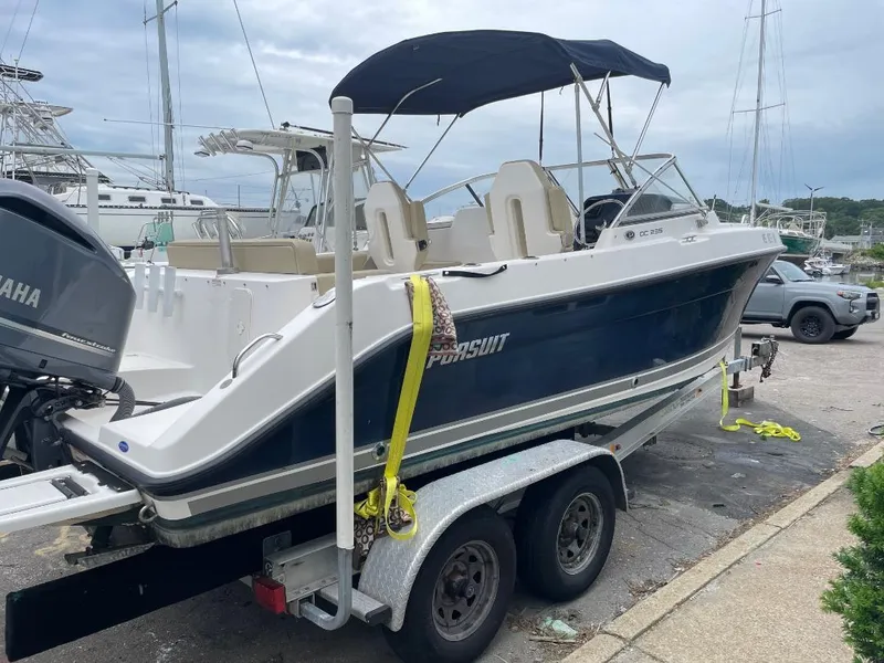 Slide: The Image of 2016 Pursuit DC 235 Dual Console boat on trailer with Yamaha engine, docked outdoors. - 2