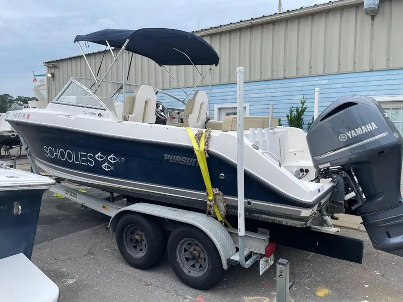Slide: The Image of 2016 Pursuit DC 235 Dual Console boat on trailer with Yamaha engine, parked outdoors. - 3