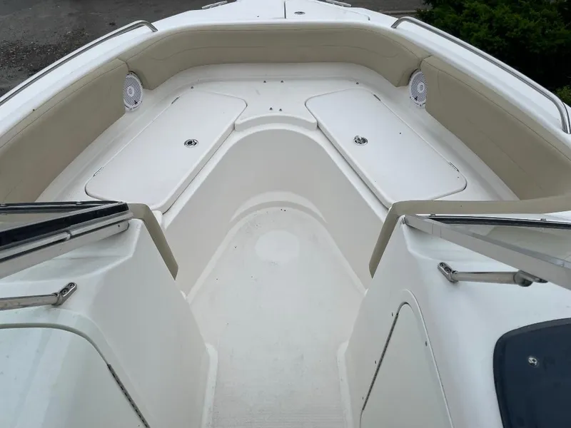 Slide: The Image of 2016 Pursuit DC 235 Dual Console boat interior with beige seating and storage compartments. - 4