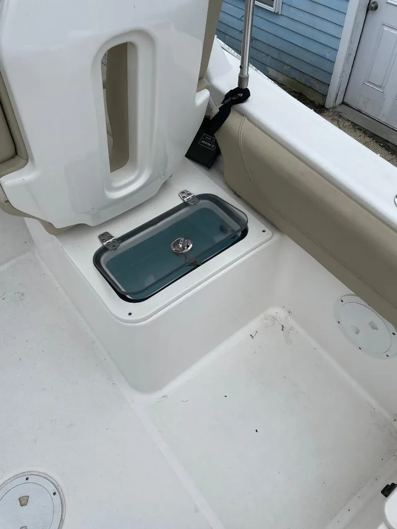 Slide: The Image of 2016 Pursuit DC 235 Dual Console boat interior with storage compartment and cushioned seating. - 7