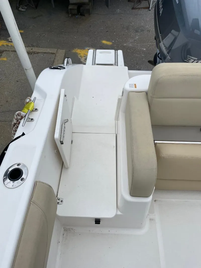 Slide: The Image of 2016 Pursuit DC 235 Dual Console boat interior with beige seating and storage compartment. - 8