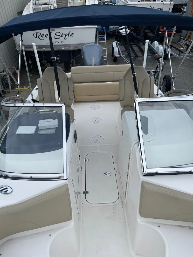 Slide: The Image of 2016 Pursuit DC 235 Dual Console boat with beige seating and blue canopy. - 9