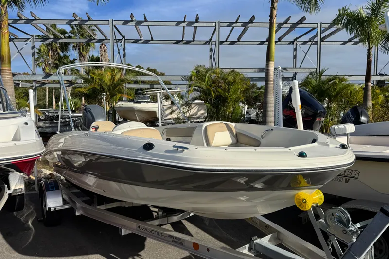The Image of 2016 Stingray 182 SC boat on trailer, surrounded by palm trees and other boats. - 1