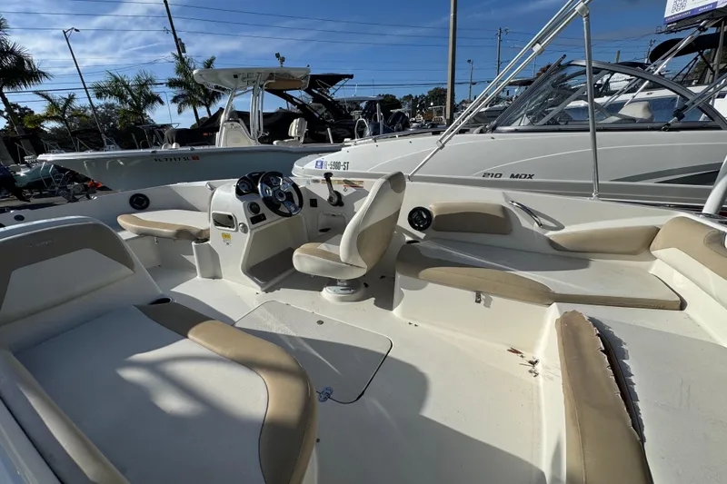 Slide: The Image of 2016 Stingray 182 SC boat interior with seating and steering console, parked outdoors. - 11