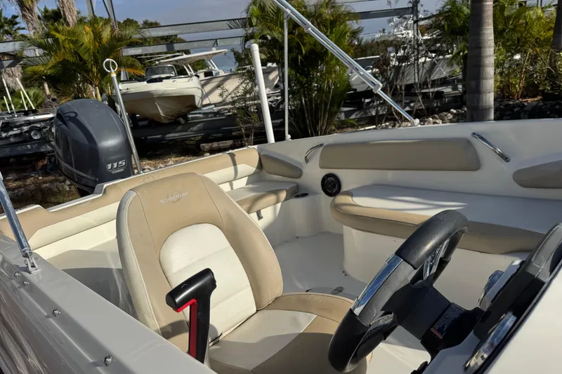 Slide: The Image of 2016 Stingray 182 SC boat interior with steering wheel and seating, parked outdoors. - 3
