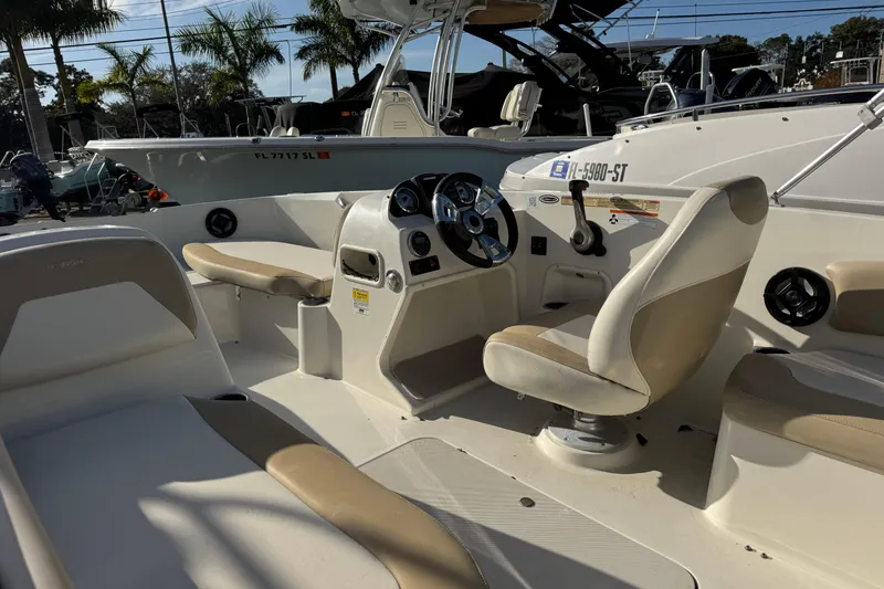 Slide: The Image of 2016 Stingray 182 SC boat interior with steering wheel and seating, parked outdoors. - 9