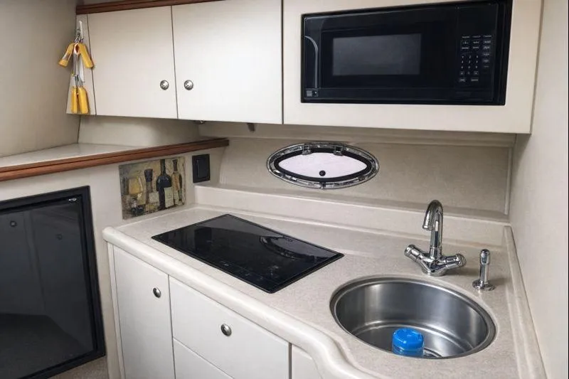 Slide: The Image of 2004 Cruisers Yachts 3372 Express kitchen with sink, stove, microwave, and storage cabinets. - 7