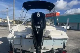 Slide: The Image of 2023 Key West 203 DFS boat with outboard motor, parked outdoors under blue sky. - 5