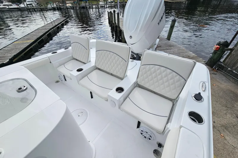 Slide: The Image of 2026 Sea Hunt BX 25 FS boat interior with cushioned seating and motor, docked by the water. - 8
