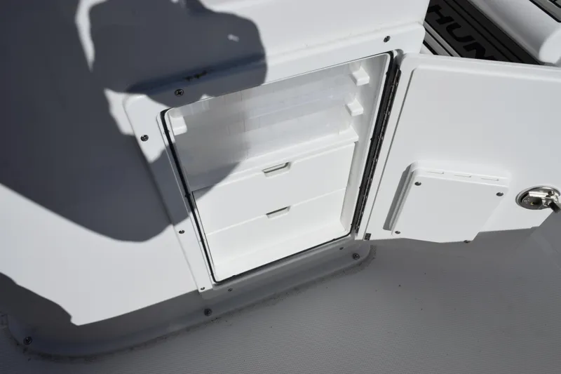 Slide: The Image of 2026 Sea Hunt BX 25 FS boat storage compartment with open door and drawers. - 27