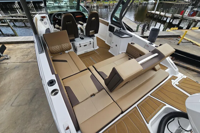 Slide: The Image of 2026 Monterey Elite 27 OB boat interior with tan seating and modern design at a dock. - 4