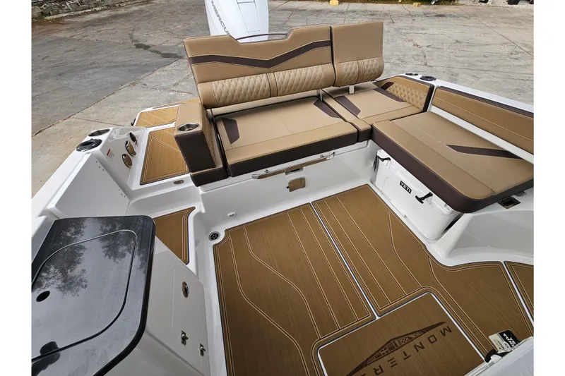 Slide: The Image of 2026 Monterey Elite 27 OB boat interior with tan seating and wood-style flooring. - 9