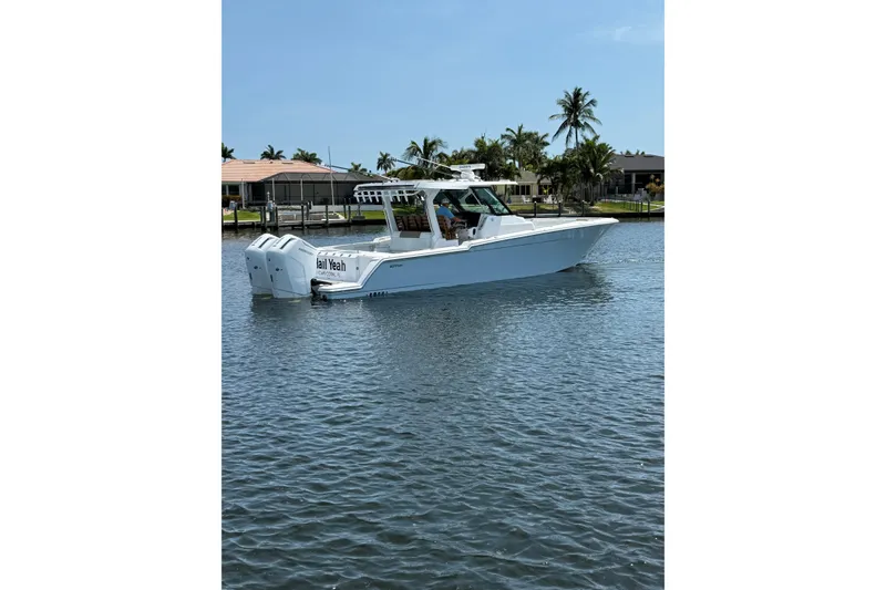 Slide: The Image of 2024 Bertram 39 CC boat on calm water, surrounded by palm trees and waterfront homes. - 56