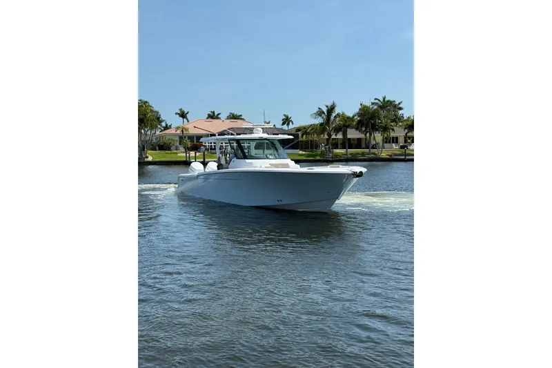 Slide: The Image of 2024 Bertram 39 CC boat cruising on a sunny day near waterfront homes. - 58