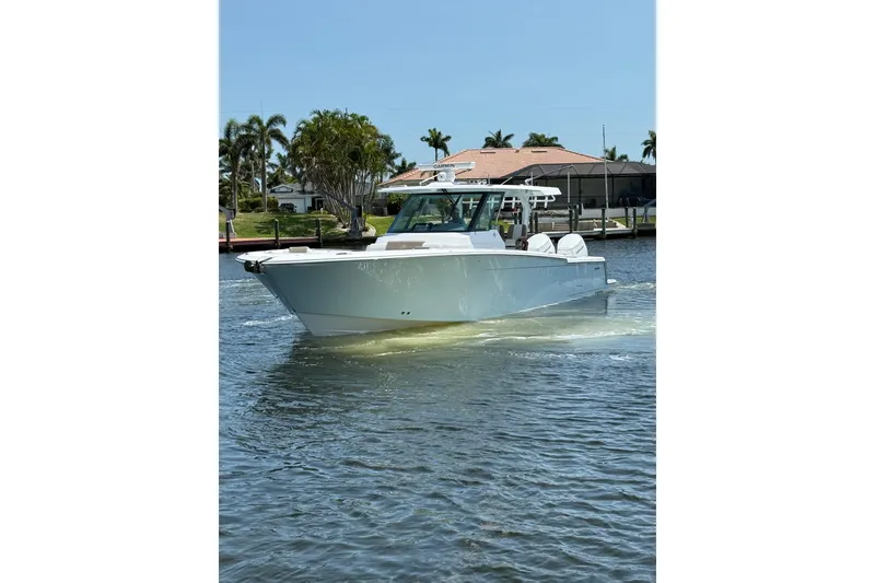 Slide: The Image of 2024 Bertram 39 CC boat cruising on a sunny day near waterfront homes. - 60