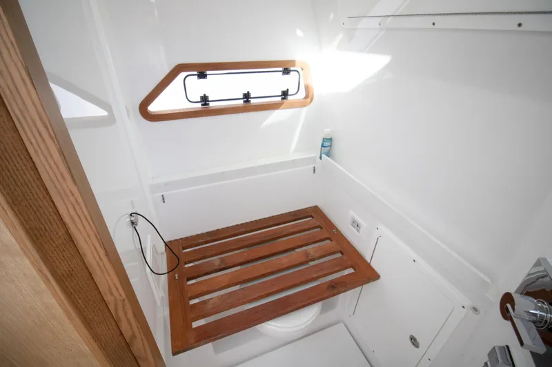 Slide: The Image of 2024 Bertram 39 CC boat bathroom with wooden seat and window. - 89