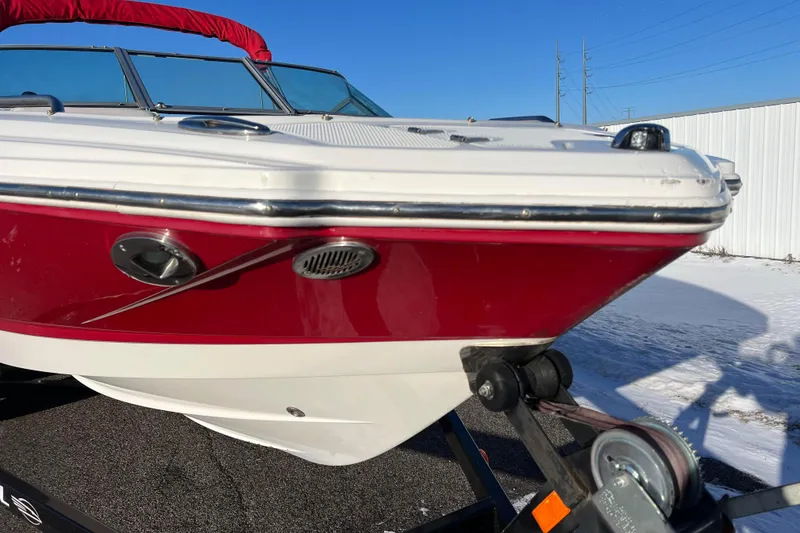 Slide: The Image of 2010 Chaparral 216 SSi boat with red and white hull on trailer, sunny day. - 15