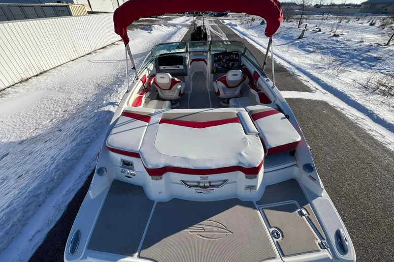 Slide: The Image of 2010 Chaparral 216 SSi boat with red and white interior, parked on snowy road. - 3
