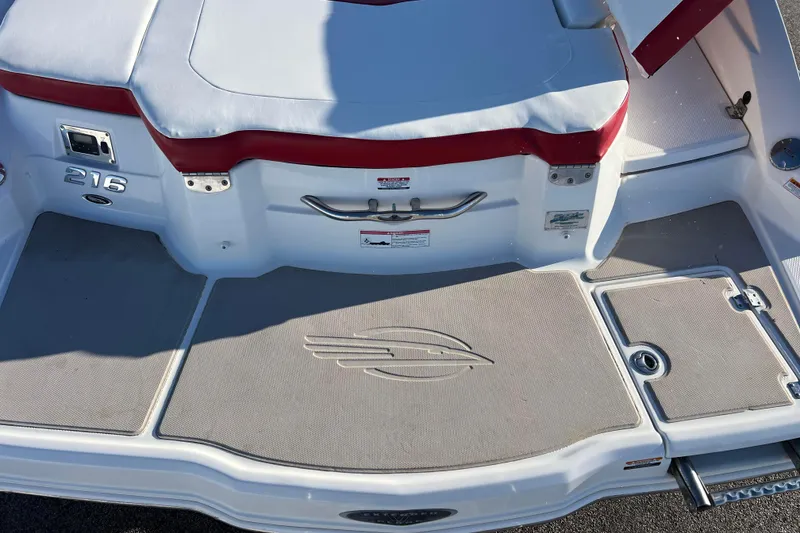 Slide: The Image of 2010 Chaparral 216 SSi boat deck with red and white seating, logo, and storage hatch. - 69