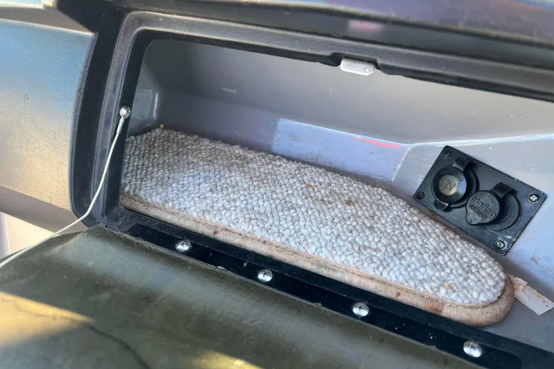 Slide: The Image of Open glove compartment in 2010 Chaparral 216 SSi boat with carpet lining and power outlet. - 75