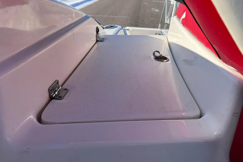 Slide: The Image of 2010 Chaparral 216 SSi boat storage compartment with latch, white and red interior. - 78