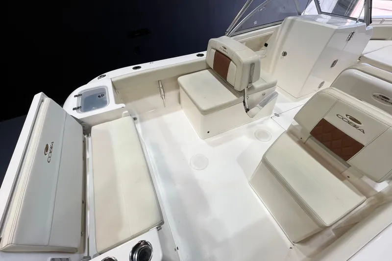 Slide: The Image of 2023 Cobia 220 Dual Console boat interior with white seating and storage compartments. - 16