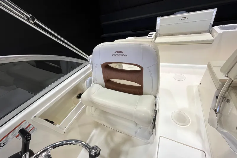 Slide: The Image of 2023 Cobia 220 Dual Console boat interior with white seating and steering wheel. - 22