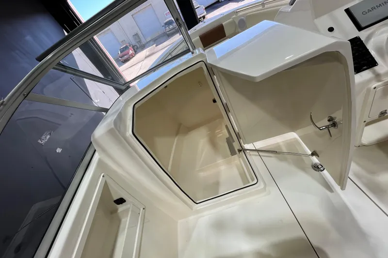 Slide: The Image of 2023 Cobia 220 Dual Console boat interior storage compartment with open hatch. - 25