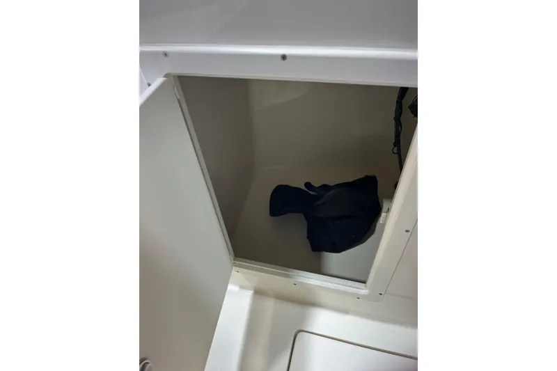 Slide: The Image of Open storage compartment in 2023 Cobia 220 Dual Console boat. - 27