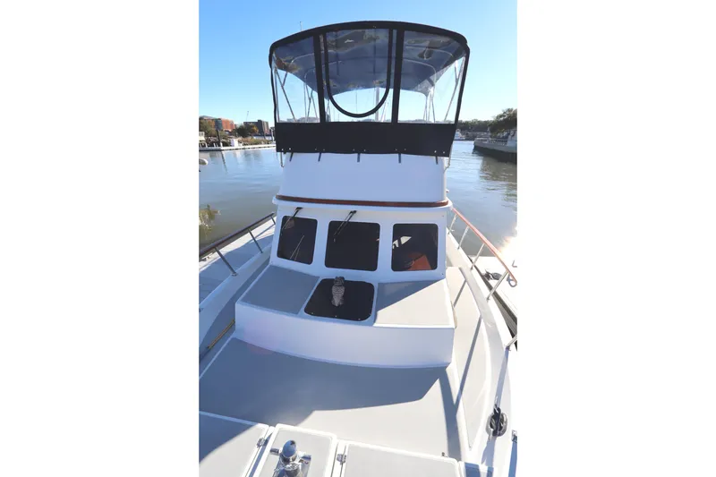 Slide: The Image of 2005 Monk 36 boat on calm water, featuring a spacious deck and enclosed helm. - 11