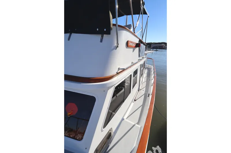 Slide: The Image of 2005 Monk 36 boat docked, showcasing upper deck and windows on a sunny day. - 17