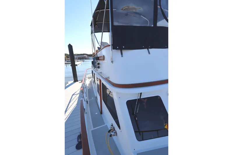 Slide: The Image of 2005 Monk 36 boat docked at marina, side view with canopy and windows. - 18
