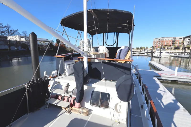 Slide: The Image of 2005 Monk 36 yacht docked at marina, featuring spacious deck and covered seating area. - 24