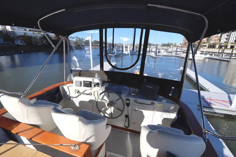 Slide: The Image of Helm of 2005 Monk 36 boat with marina view, featuring dual seats and navigation equipment. - 28