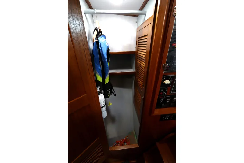 Slide: The Image of Wooden closet interior on a 2005 Monk 36 boat, featuring shelves and hanging life jackets. - 65