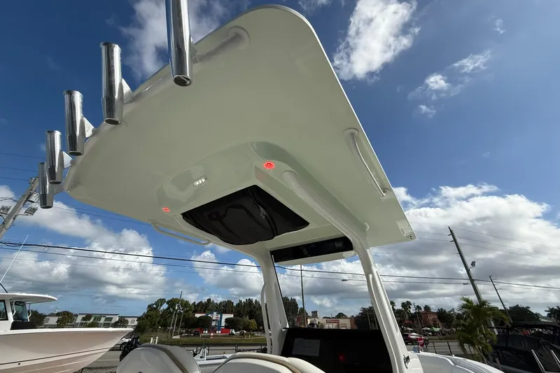 Slide: The Image of 2021 Edgewater 262CC boat with T-top and rod holders under a clear sky. - 16