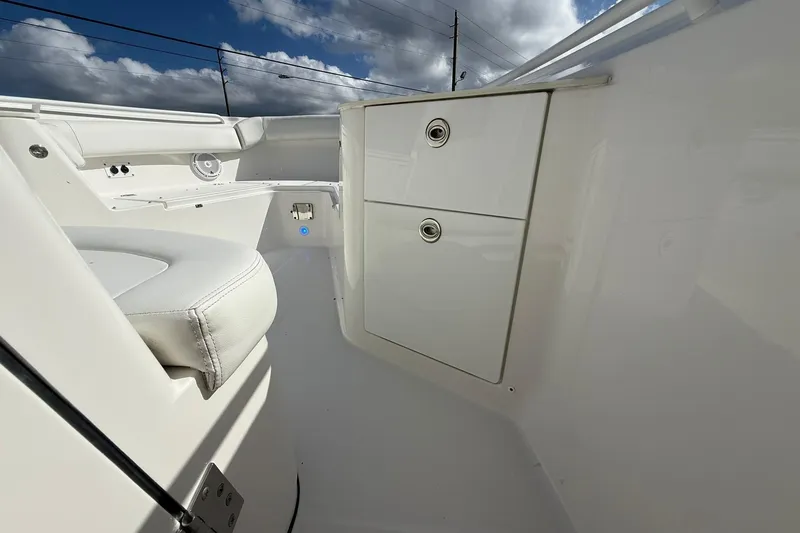 Slide: The Image of 2021 Edgewater 262CC boat interior with storage compartments and seating under a cloudy sky. - 26