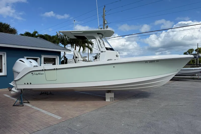 Slide: The Image of 2021 Edgewater 262CC boat on display, light green hull, parked outdoors. - 5