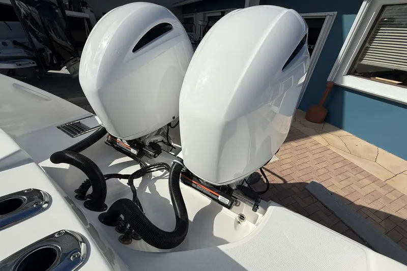 Slide: The Image of Twin outboard engines on a 2021 Edgewater 262CC boat, docked on a sunny day. - 8