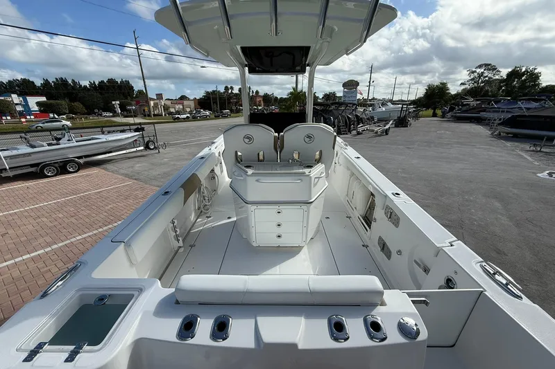 Slide: The Image of 2021 Edgewater 262CC boat interior with seating and storage, parked outdoors. - 9