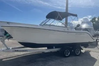 Slide: The Image of 2023 Cobia 220 Dual Console boat on trailer, parked outdoors under blue sky. - 4