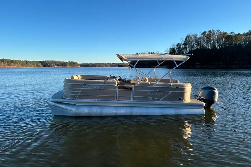 Slide: The Image of 2022 Godfrey Sweetwater 2286 C pontoon boat on a serene lake under clear blue skies. - 4