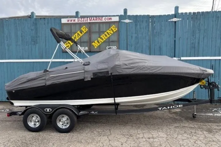 Slide: The Image of 2019 Tahoe 500 TS boat covered on trailer, parked by blue fence. - 28