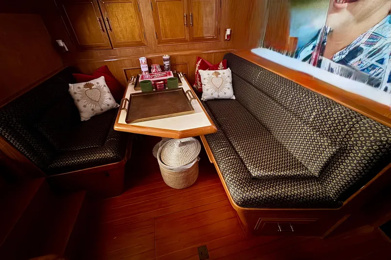 Slide: The Image of Cozy 1988 Carmague 48 CPMY yacht interior with cushioned seating and wooden cabinetry. - 10