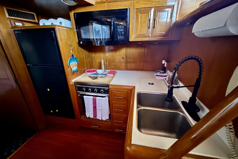 Slide: The Image of 1988 Carmague 48 CPMY yacht kitchen with wooden cabinets, dual sink, and modern appliances. - 11
