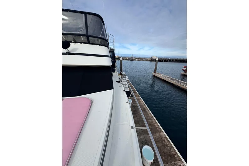 Slide: The Image of 1988 Carmague 48 CPMY yacht docked at marina, view of deck and calm water. - 24